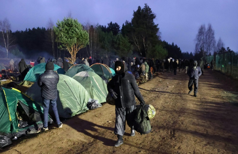 مهاجرون يسعون للعبور إلى بولندا يتلقون الفطور في مخيم قرب معبر بروزغي-كوشنيتسا من الجانب البيلاروسي للحدود بين البلدين في 18 تشرين الثاني/نوفمبر 2021(ا ف ب)