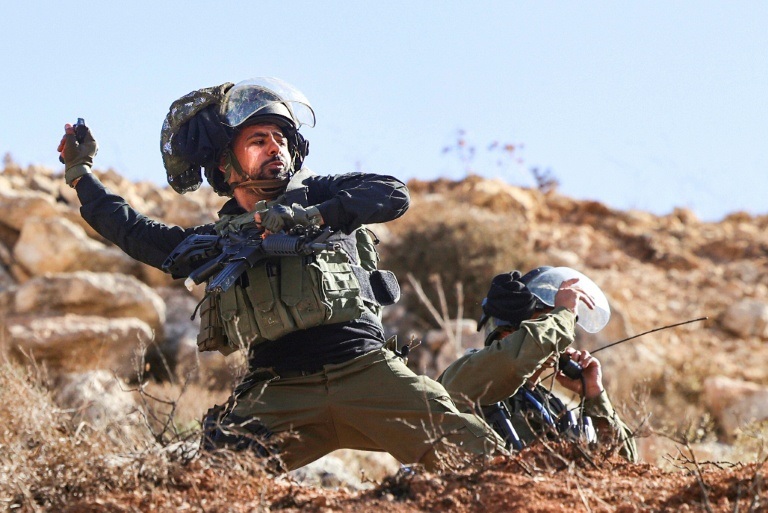 أحد الجنود الاسرائيليين وهم يهم بقذف قنبلة دخانية باتجاه المتظاهرين الفلسطينيين ( أ ف ب - أرشيفية)