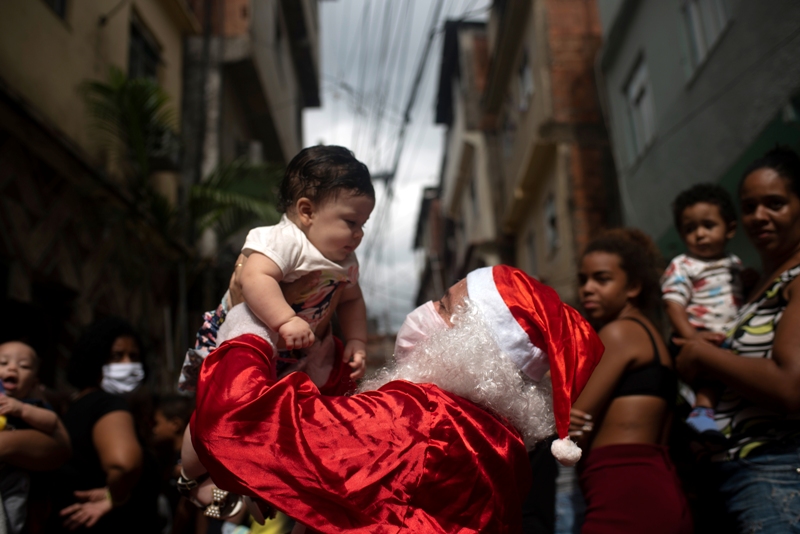 رجل يرتدي زي بابا نويل يزور الأحياء الفقيرة في راموس لتوزيع الحلوى والألعاب على أطفال فافيلا في يوم عيد الميلاد (د ب أ)