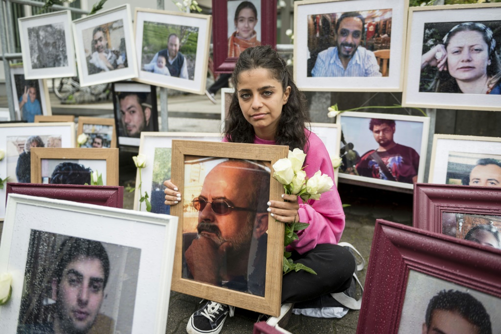    الناشطة السورية وفاء مصطفى تعرض صور ضحايا النظام السوري وهي تحمل صورة والدها المفقود (أ ف ب)