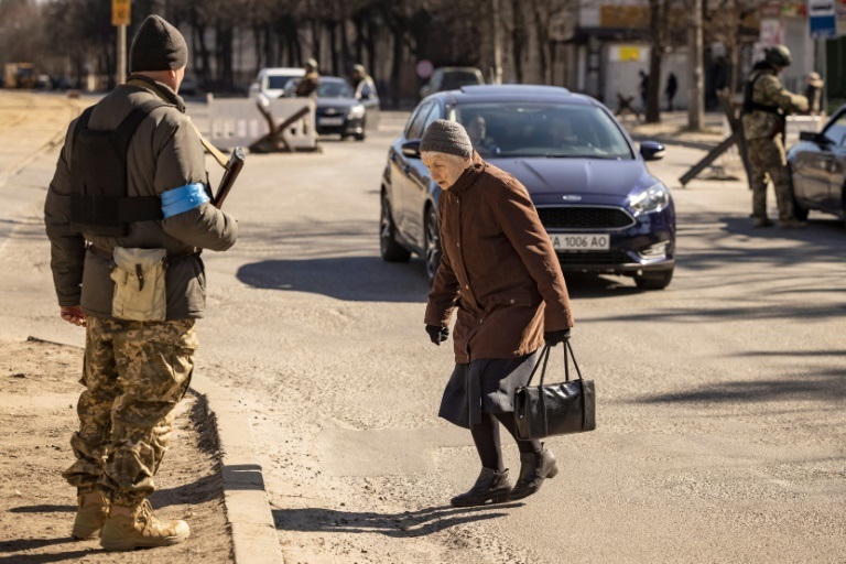 امرأة تمر امام عناصر من قوات الأمن الاوكرانية عند نقطة تفتيش في كييف في 21 آذار/مارس 2022 (ا ف ب)