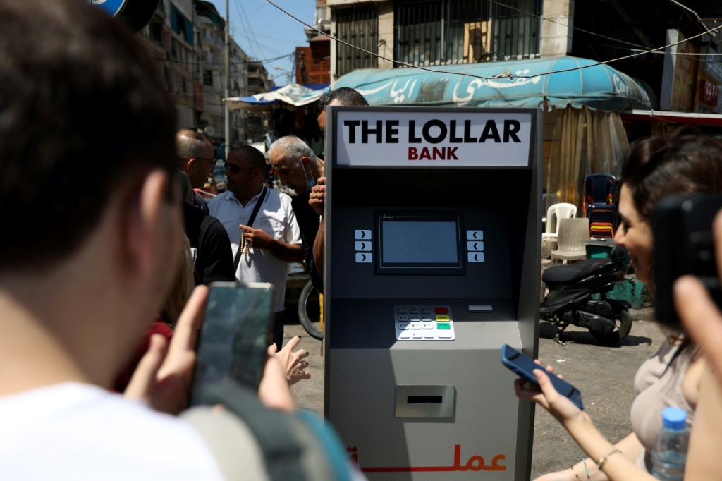    لبنانيون يحاصرون صراف آلي وهمي ويوزعون أوراق نقدية مزيفة تسمى "لولارز" (أ ف ب)