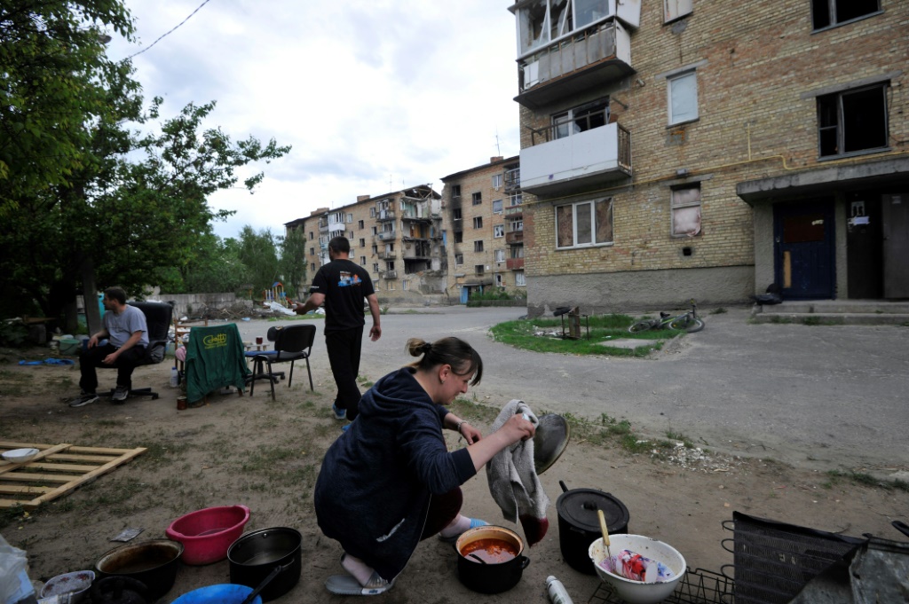 سيدة أوكرانية تعد الطعام في الشارع أمام منزلها الذي قصف في مدينة موشوم الصغيرة بالقرب من كييف في 27 أيار/مايو 2022 (أ ف ب)