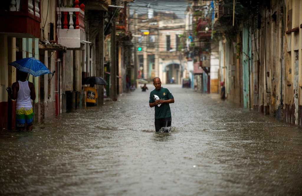 رجل يمشي وسط شارع غمرته المياه في كوبا في 3 حزيران/يونيو 2022 (ا ف ب)