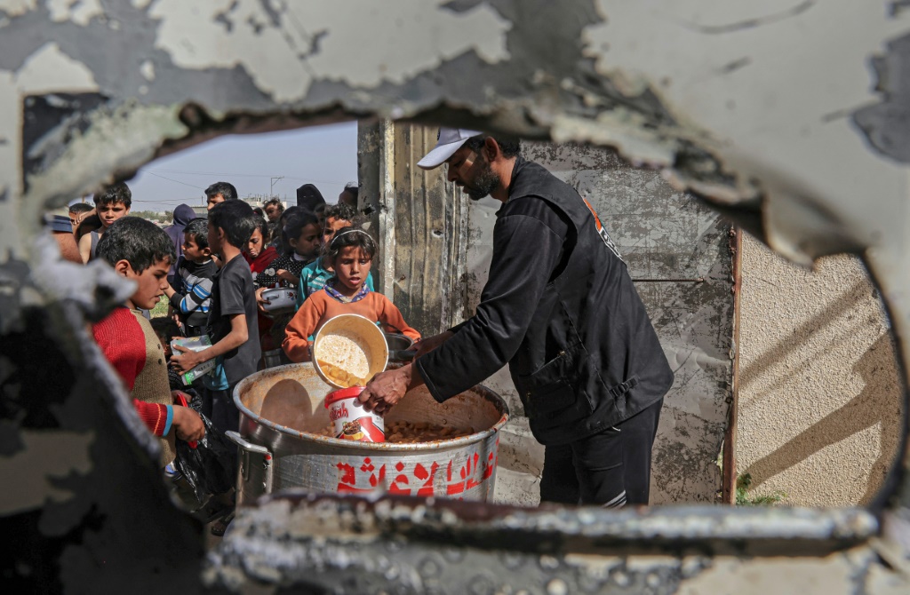 أطفال فلسطينيون في قطاع غزة المحاصر من قبل إسرائيل يصطفون للحصول على وجبات مجانية لكسر الصيام خلال شهر رمضان المبارك (ا ف ب)