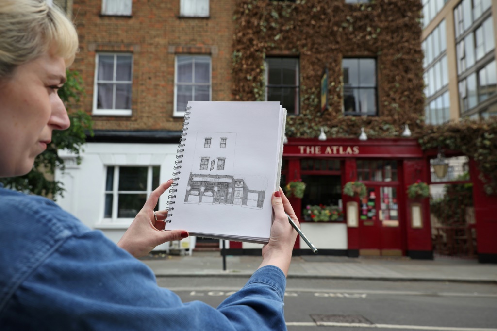 الفنانة البريطانية ليديا وود أمام مقهى "ذي أطلس" بعيد رسمها إياه في 26 أيار/مايو 2022 في العاصمة البريطانية لندن (ا ف ب)