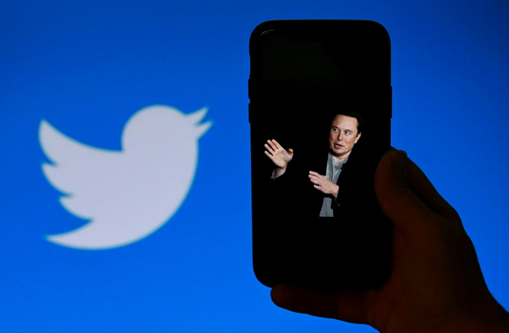 صورة لإيلون ماسك على هاتف نقال بينما يظهر شعار تويتر في الخلفية في واشنطن بتاريخ 4 تشرين الأول/أكتوبر 2022 (ا ف ب)