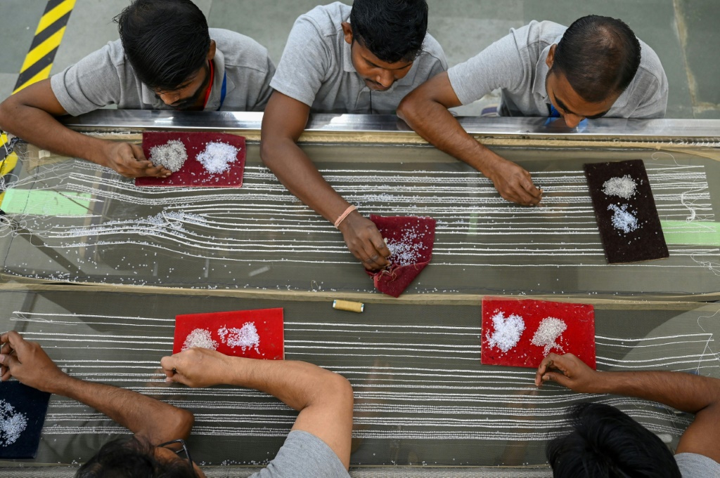عمال في مشغل شاناغار يشكون الخرز على قطعة من القماش في بومباي الهندية بتاريخ السابع من كانون الثاني/يناير 2023 (ا ف ب)