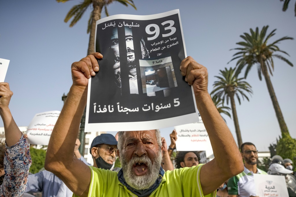    ناشطون يرفعون لافتة تحمل صورة سليمان الريسوني خلال تظاهرة مؤيدة للصحافي في الرباط بتاريخ 10 تموز/يوليو 2021 (أ ف ب)