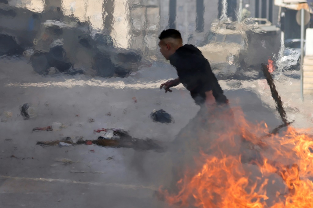    متظاهر فلسطيني يركض بين إطارات مشتعلة خلال مواجهات مع القوات الإسرائيلية خلال اقتحامها البلدة القديمة في مدينة نابلس شمال الضفة الغربية المحتلة في 30 كانون الاول/ديسمبر2022 (ا ف ب)