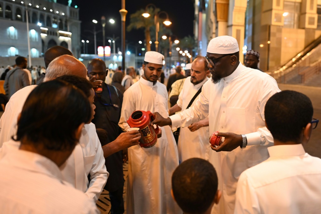     الموظف السعودي عامر عبدالله يوزع أكواب الشاي على الحجاج قرب المسجد الحرام في مكة المكرمة في 23 حزيران/يونيو 2023 (أ ف ب)   