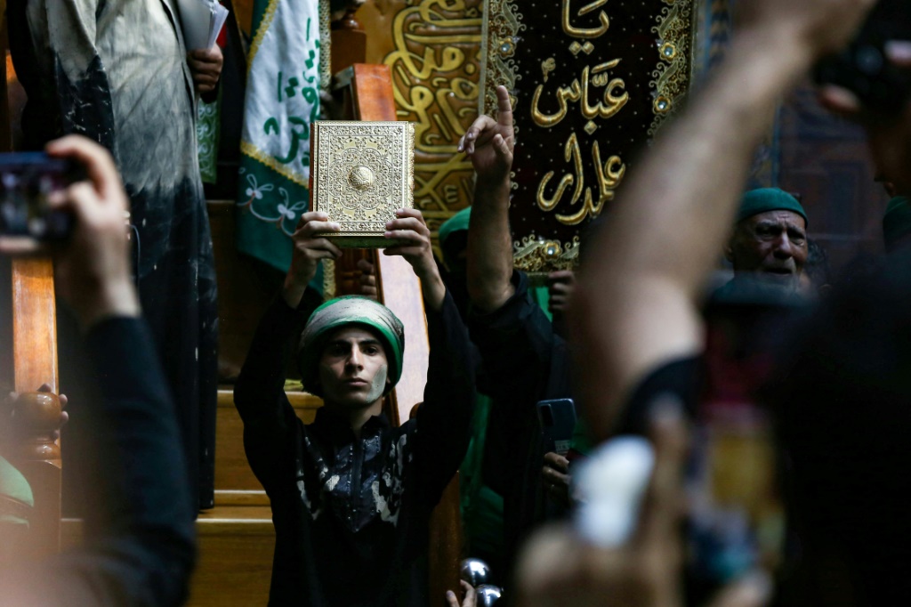     رجل يرفع القرآن في كربلاء خلال إحياء مراسم عاشوراء في 28 تموز/يوليو 2023 (أ ف ب)   
