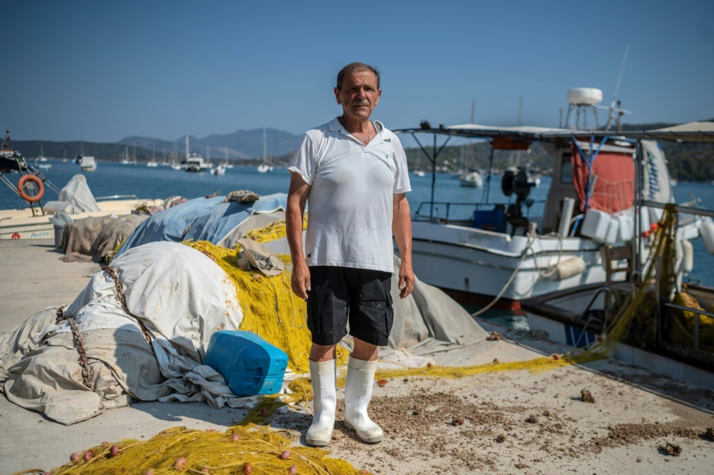 الصياد اليوناني سبيروس بابايوانو قرب قاربه في جزيرة بوروس في الخامس من تموز/يوليو 2023 (ا ف ب)