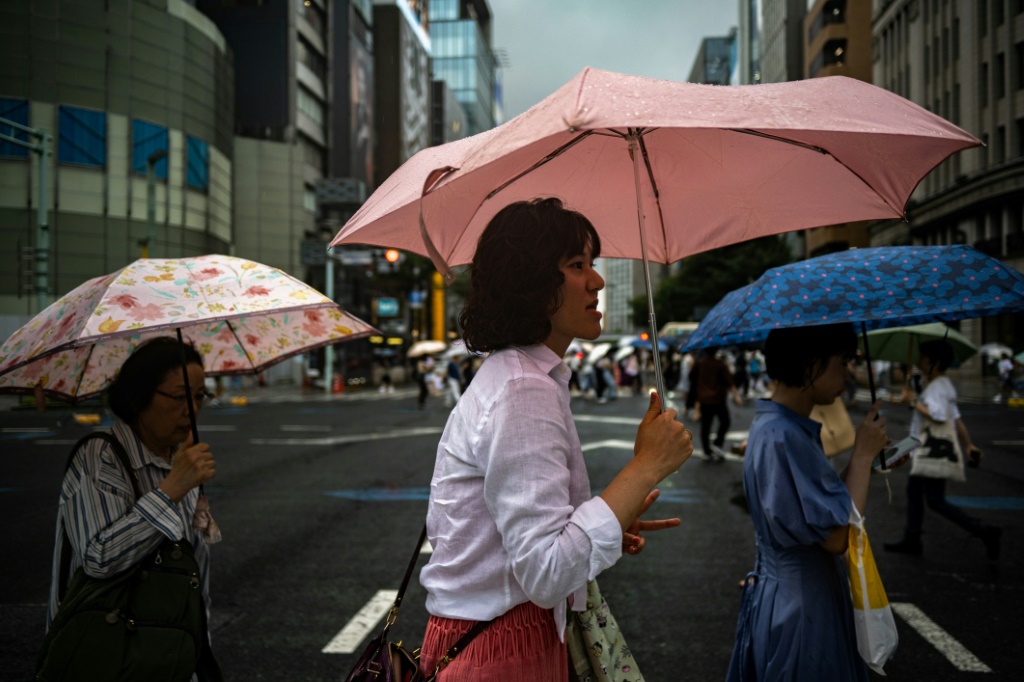 أشخاص يحملون مظلاتهم في ظل تساقط الأمطار في طوكيو بتاريخ 13 آب/اغسطس 2023 مع اقتراب الإعصار لان من جزيرة هونشو الرئيسية (ا ف ب)