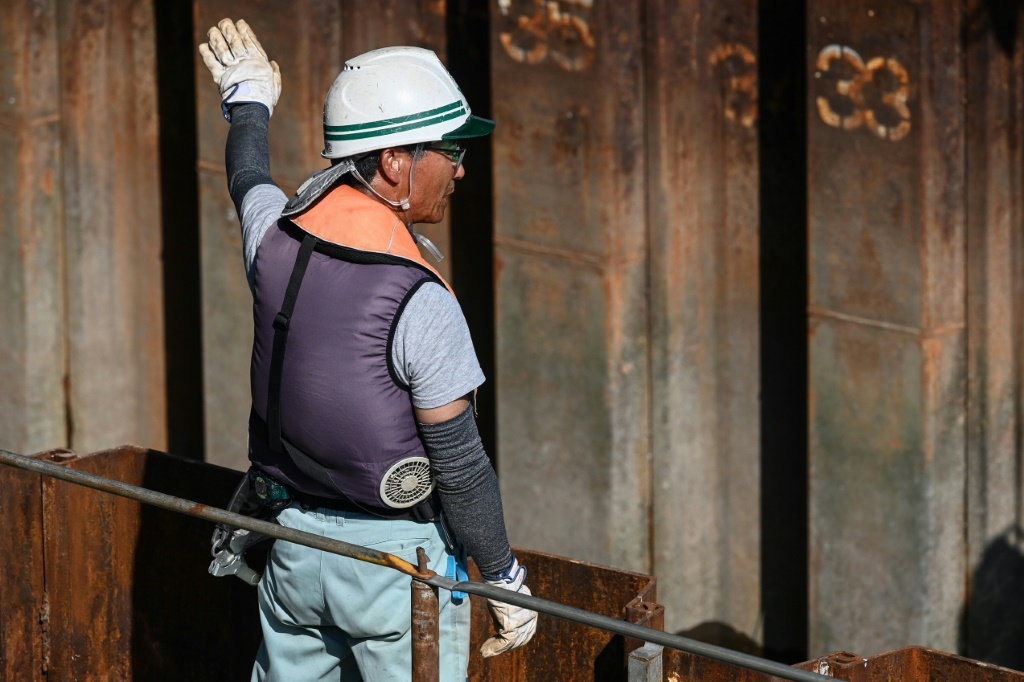 عامل يرتدي سترة مزوّدة بمراوح تعمل بالبطارية في العاصمة اليابانية طوكيو بتاريخ الرابع من آب/أغسطس 2023 (ا ف ب)