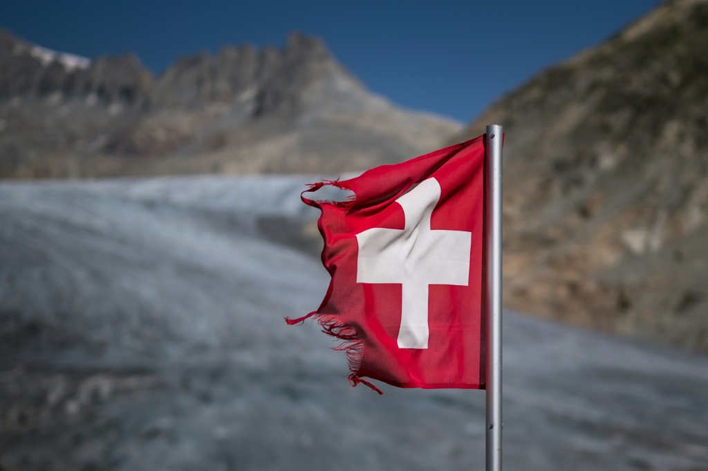 صورة ملتقطة في 24 آب/أغسطس 2023 في الألب السويسرية تظهر علم سويسرا قرب نهر رون الجليدي حيث يُسجل ذوبان متسارع للجليد (ا ف ب)