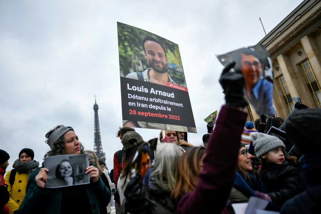 أشخاص يرفعون صورا تظهر الفرنسية سيسيل كولر (يسار) والفرنسي لوي أرنو (وسط) المعتقلين في إيران، خلال تظاهرة دعم في باريس في 28 كانون الثاني/يناير 2023 (أ ف ب)   