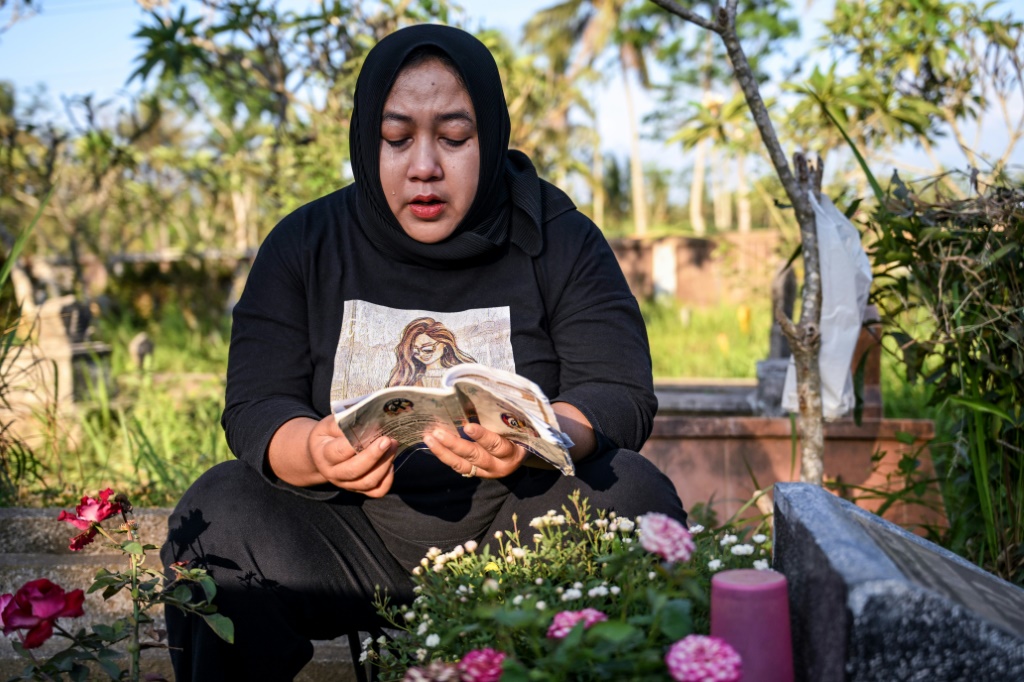 تشوليفاتول نور تصلي على قبر طفلها الوحيد، جوفان فاريلينو، الذي كان يبلغ من العمر 15 عامًا عندما توفي في التدافع الذي أودى بحياة 135 شخصًا في ملعب كانجوروهان لكرة القدم. (ا ف ب)   