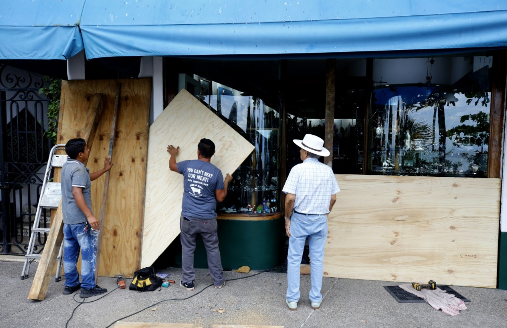 عمال يحصّنون واجهات متاجرهم بألواح خشبية تحسّباً لوصول الإعصار ليديا في بويرتو فالارتا في المكسيك في 10 ت1/أكتوبر 2023 (ا ف ب)