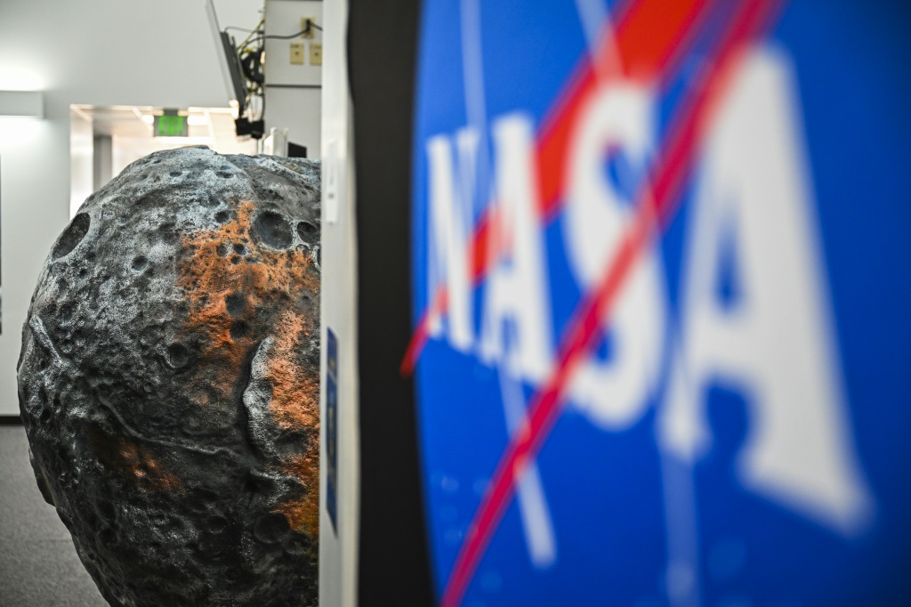شعار ناسا أمام مجسّم لكويكب سايكي في مركز كينيدي الفضائي في فلوريدا بتاريخ العاشر من تشرين الأول/اكتوبر 2023(أ ف ب)   