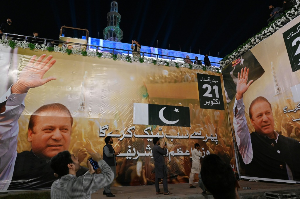 أنصار رئيس الوزراء الباكستاني السابق نواز شريف يتجمّعون بجانب لافتات كبيرة لشريف للترحيب به قبل وصوله إلى لاهور في 20 تشرين الأول/أكتوبر 2023 (أ ف ب)   