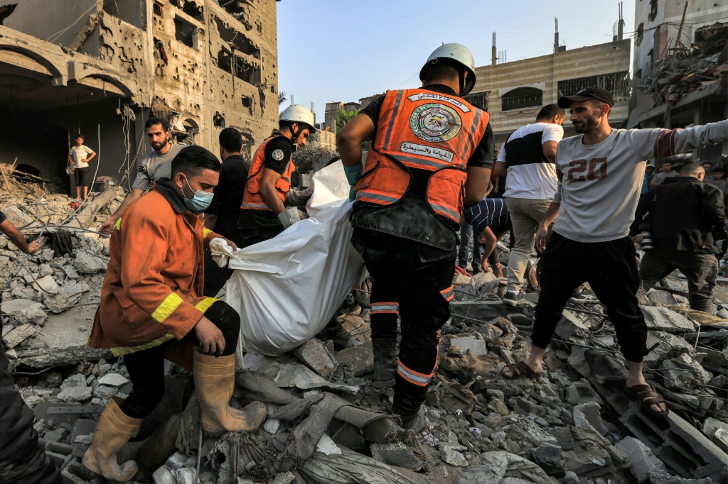 مسعفون فلسطينيون ينقلون جثة أحد الضحايا من تحت أنقاض مبنى أصيب بقصف إسرائيلي في بلدة خان يونس جنوب قطاع غزة.(أ ف ب)   