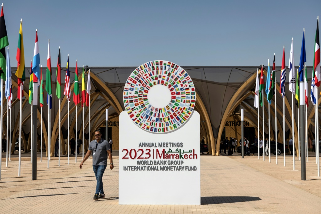 رجل يسير بجوار شعار الاجتماعات السنوية لصندوق النقد الدولي والبنك الدولي للعام 2023 في مراكش في الثامن من تشرين الأول/أكتوبر 2023 (ا ف ب)