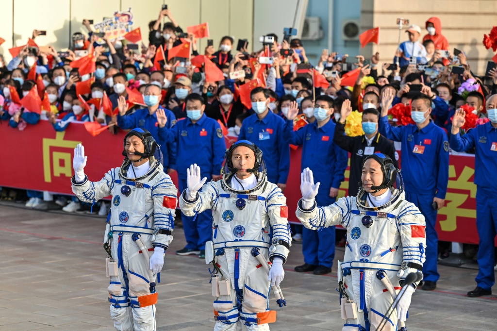 غوي هايشاو (يسار) وتشو يانغتشو (وسط) وجينغ هايبنغ (يمين) يلوّحون بأيديهم خلال مراسم قبل انطلاق المهمة شنتشو-19 في موقع الإطلاق جيوتشيوان بمقاطعة غانسو في شمال غرب الصين في 30 أيار/مايو 2023 (ا ف ب)