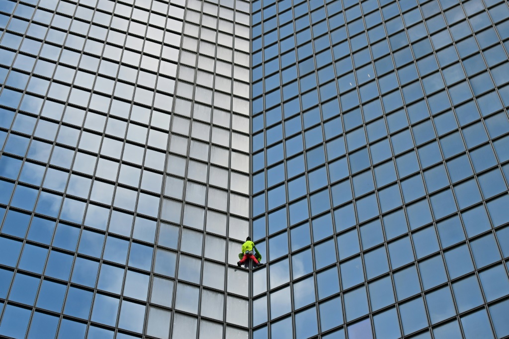 "الرجل العنكبوت الفرنسي" آلان روبير يتسلق برج "كوبول توتال" مقر شركة "توتال إنرجي" النفطية في حي لا ديفانس في غرب باريس في السادس من تشرين الثاني/نوفمبر 2023 (ا ف ب)