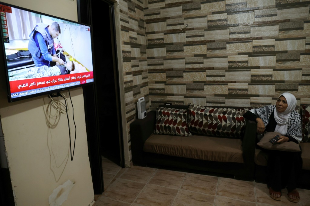  اللاجئة الفلسطينية فاطمة الشواح تتابع عبر شاشة التلفاز أخبار الحرب في قطاع غزة، في صورة مؤرخة 15 تشرين الثاني/نوفمبر 2023 (ا ف ب)