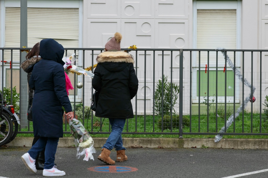 أشخاص يحملون الزهور لوضعها أمام منزل شهد جريمة قتل جماعية أودى فيها رجل بحياة زوجته وأطفالهما الأربعة في مو قرب العاصمة الفرنسية باريس في 26 كانون الأول/ديسمبر 2023 (ا ف ب)