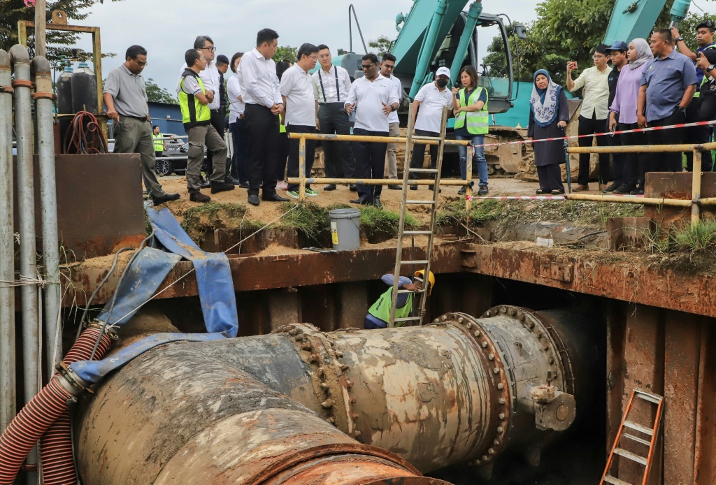 عمال يصلحون صمامات المياه في منشأة سونغاي دوا لمعالجة بمقاطعة بينانغ في شمال ماليزيا في 10 كانون الثاني/يناير 2024. (ا ف ب)