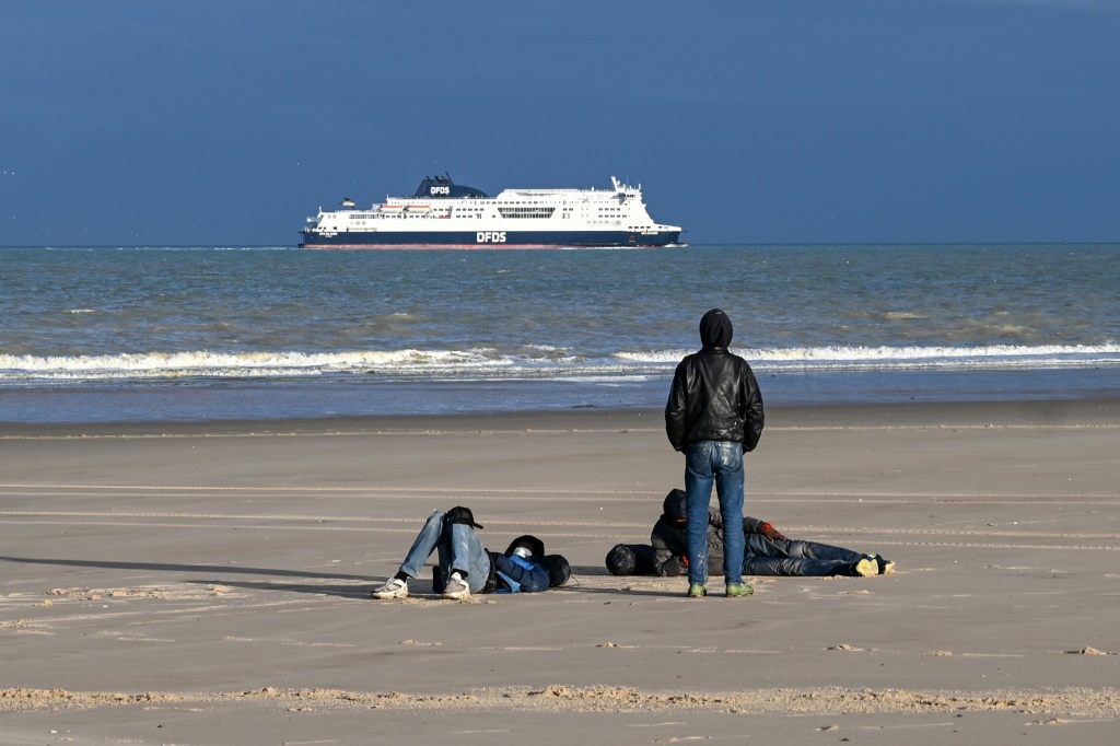 مهاجرون يتجمعون على الشاطئ بعد فشلهم في عبور القناة الإنجليزية بشكل غير قانوني للوصول إلى بريطانيا، في سانجات، شمال فرنسا، في ديسمبر 2023. (أ ف ب)   