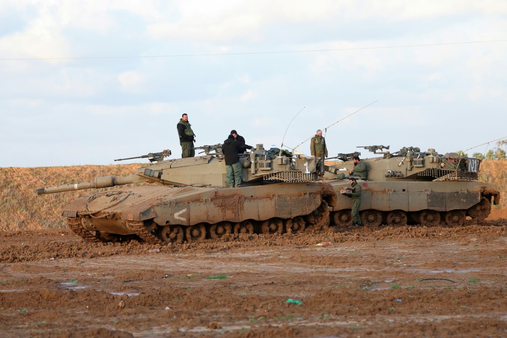 جنود إسرائيليون يقفون على دبابة في موقع في جنوب إسرائيل قرب الحدود مع قطاع غزة مع استمرار القتال بين إسرائيل وحركة حماس، في 12 كانون الثاني/يناير 2024. (ا ف ب)