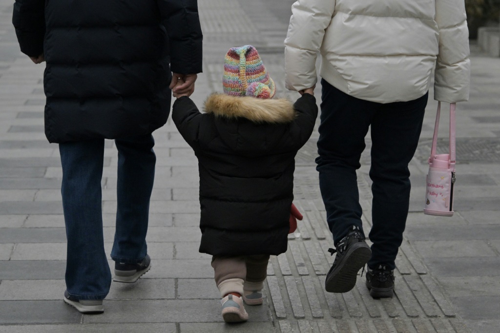 طفل مع بالغين في أحد شوارع بكين بتاريخ 17 كانون الثاني/يناير 2024 (ا ف ب)