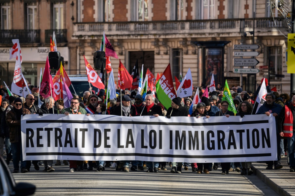 متظاهرون يحملون لافتة تدعو الى سحب قانون الهجرة خلال تظاهرة في تولوز بجنوب فرنسا في 20 كانون الثاني/يناير 2024 (ا ف ب)