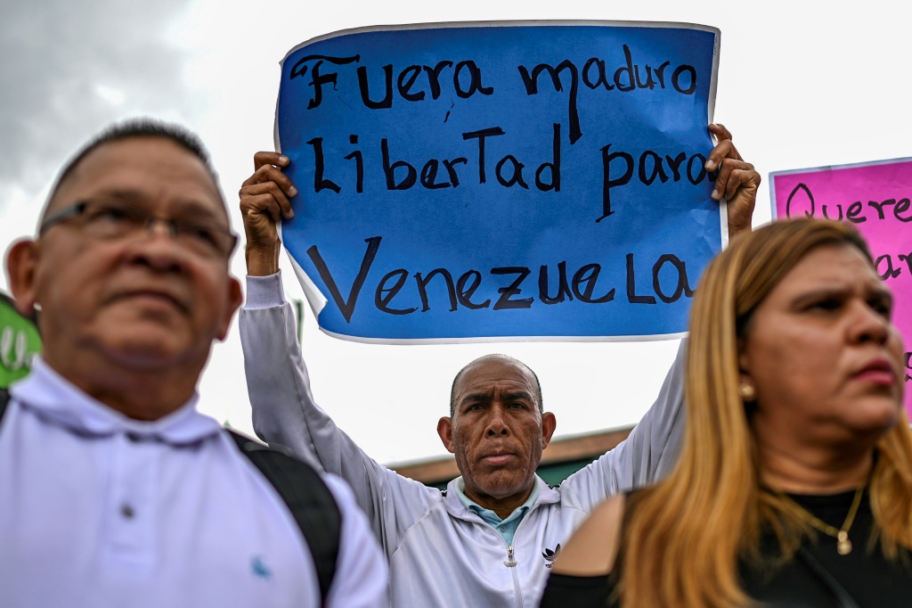 أحد مؤيدي المعارضة ماريا كورينا ماتشادو يرفع لافتة كتب عليها "مادورو إرحل" خلال تظاهرة في بوغوتا في 4 شباط/فبراير 2024 (ا ف ب)