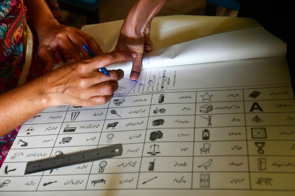 امرأة تضع بصمة الإصبع على ورقة اقتراع في كراتشي خلال الانتخابات الوطنية والمحلية في باكستان الأسبوع الماضي. (ا ف ب)