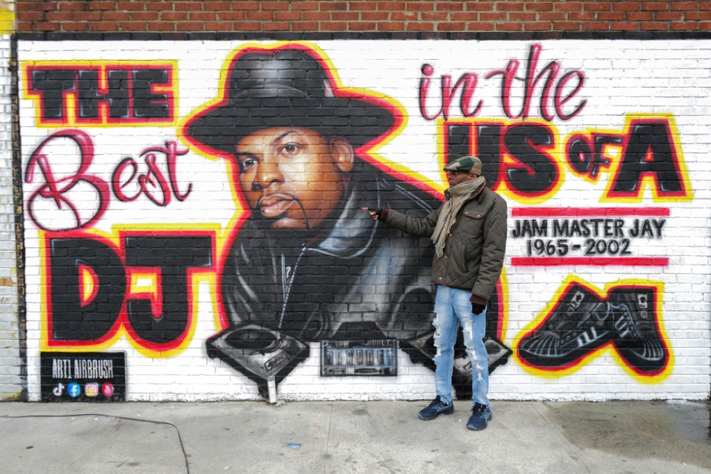 يقف جاكوب روستين، أحد السكان المحليين، أمام لوحة جدارية تكريمًا للراحل Jam Master Jay من Run-DMC في حي هوليس في كوينز، مع بدء المحاكمة في مقتل الفنان (ا ف ب)