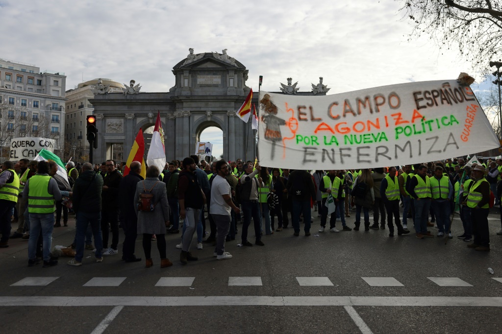 صورة مؤرخة في 21 شباط/فبراير 2024 لمزارعين يحملون لافتة احتجاجية على أوضاعهم في مدريد (أ ف ب)   
