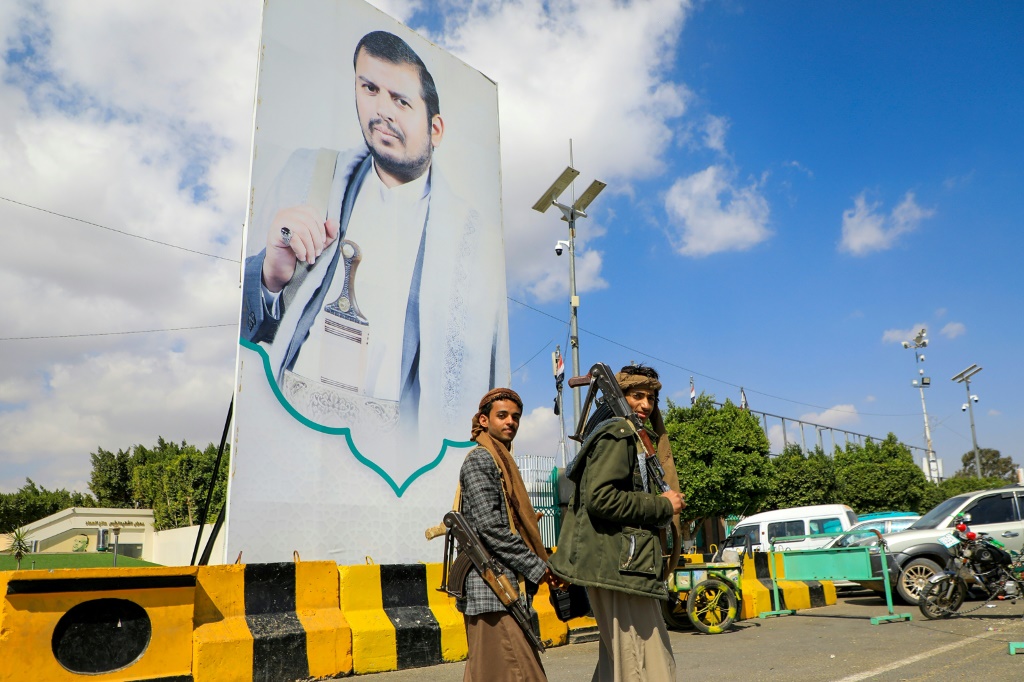 مقاتلان يمنيان يمران أمام لافتة ضخمة لزعيم الحوثيين عبد الملك الحوثي في أحد شوارع صنعاء في 18 كانون الثاني يناير 2024 (ا ف ب)