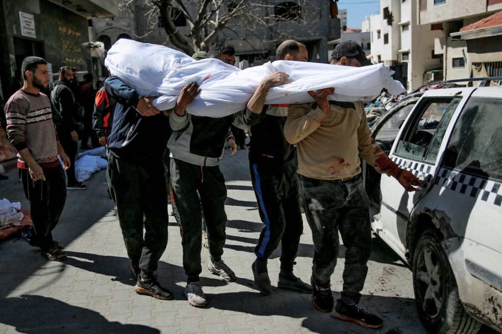 رجال يحملون جثة فلسطيني قُتل مع أكثر من مئة شخص خلال التدافع وعندما فتحت القوات الإسرائيلية النار على حشود اقتربت من شاحنات مساعدات عند نقطة توزيع في مدينة غزة في 29 شباط/فبراير 2024 (ا ف ب)