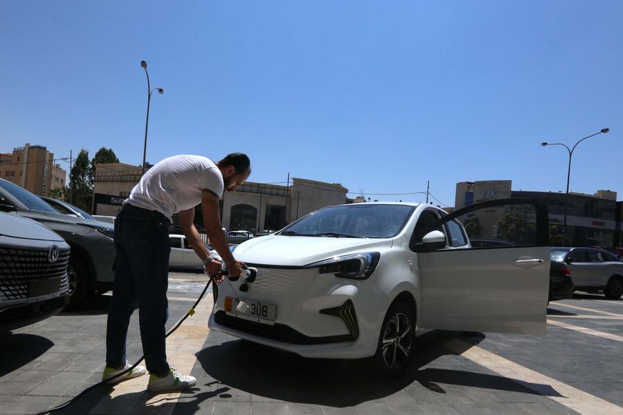 مدير مبيعات يقوم بشحن سيارة كهربائية من إنتاج شركة تشانغآن الصينية لصناعة السيارات في مركز لأحد وكلاء بيع السيارات في عمان بالأردن، 15 أغسطس 2022. (شينخوا)