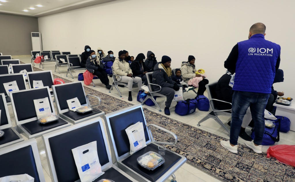    موظف من المنظمة الدولية للهجرة يساعد مهاجرين غير شرعيين قدموا من نيجيريا قبيل ترحيلهم من العاصمة الليبية طرابلس بتاريخ 30 كانون الثاني/يناير 2024 (أ ف ب)   
