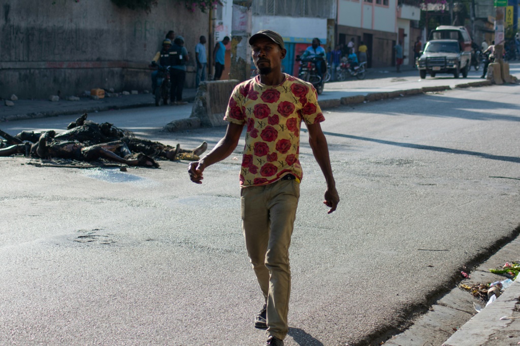 رجل يسير قرب جثث متفحمة في أحد شوارع هايتي في 22 آذار/مارس 2024 (أ ف ب)   