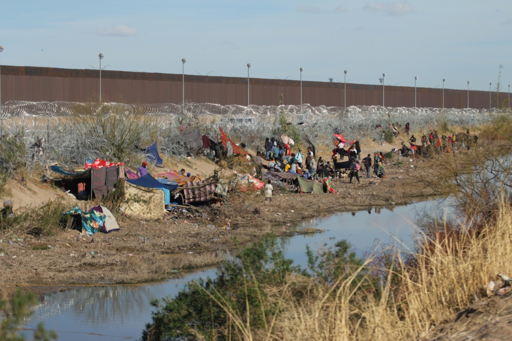 مهاجرون على الجانب المكسيكي من الحدود ينتظرون العبور إلى الولايات المتحدة عند نقطة بالقرب من إل باسو، تكساس، في 19 مارس 2024. (أ ف ب)   