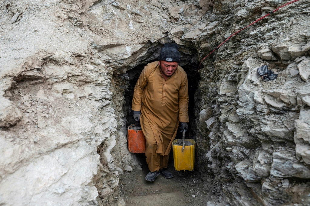 صورة ملتقطة في 24 شباط/فبراير 2024 تظهر رجلاً أفغانياً يحمل حاويات مملوءة بالحجارة والتراب من نفق في منجم للذهب في جبال منطقة يفتال سفله في ولاية بدخشان الأفغانية. (ا ف ب)