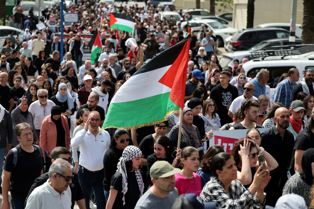 يلوحون بالعلم الفلسطيني خلال مسيرة يوم الارض في ذكراه ال48 في بلدة دير حنا في الجليل الاسفل في 30 اذار/مارس 2024 (أ ف ب)   