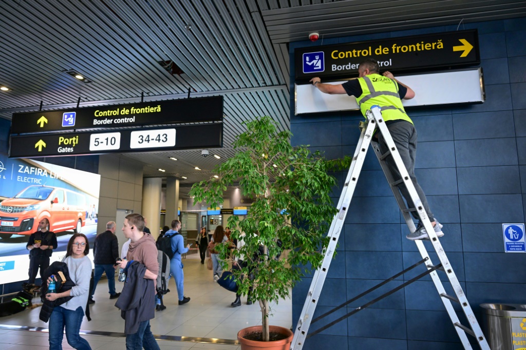 عامل روماني يغير اللافتات للمسافرين في مطار هنري كواندا الدولي قبل أن تتخذ رومانيا وبلغاريا الخطوة الأولى نحو منطقة السفر بدون تأشيرة شنغن يوم الأحد (أ ف ب)   