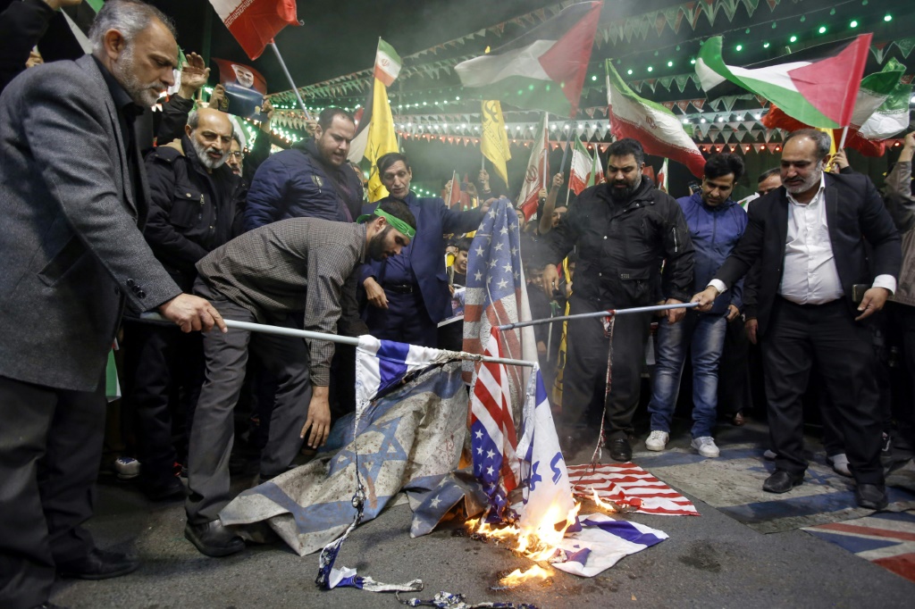 إيرانيون يحرقون الأعلام الإسرائيلية والأمريكية خلال احتجاج في ساحة فلسطين في طهران، في 1 نيسان/أبريل، 2024 إثر ضربات جوية إسرائيلية دمرت مبنى القنصلية الإيرانية في دمشق (أ ف ب)   